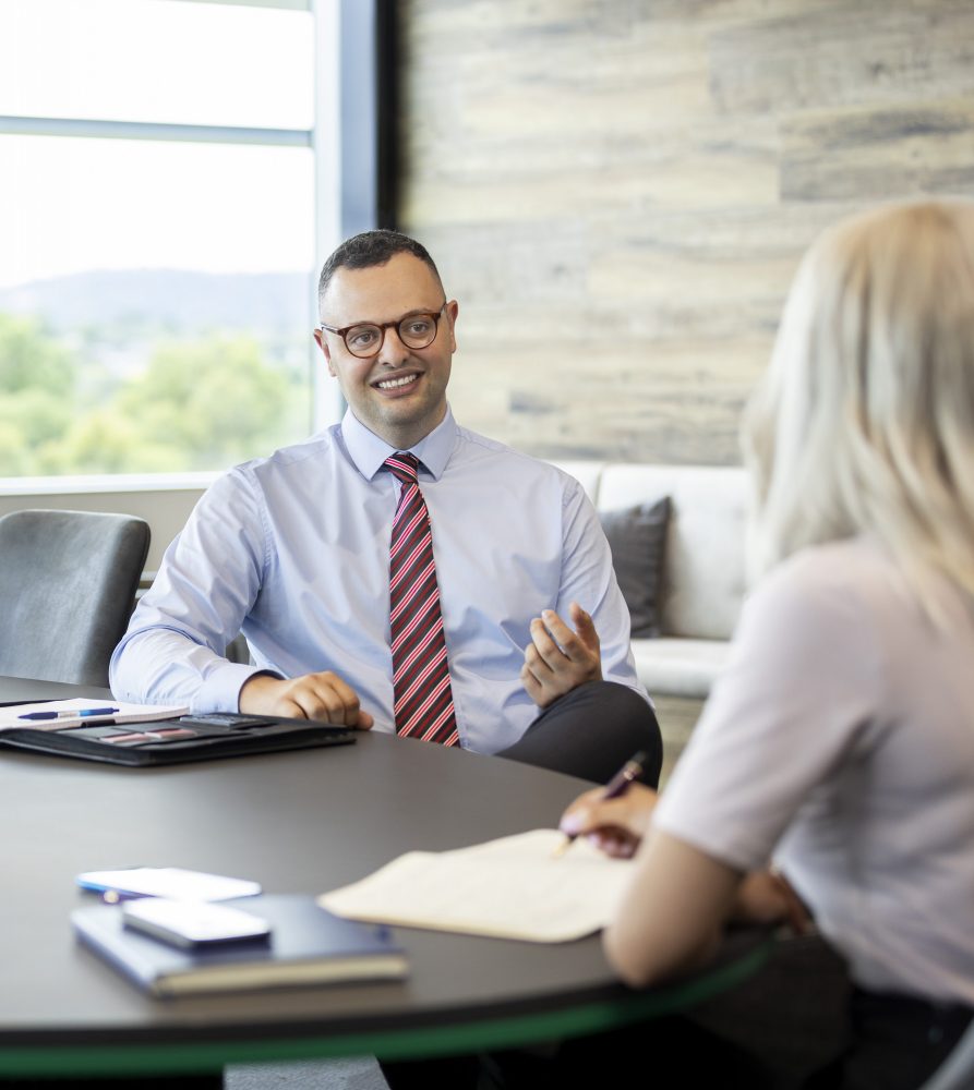 Body corporate manager conducting annual general meeting in boardroom with clients